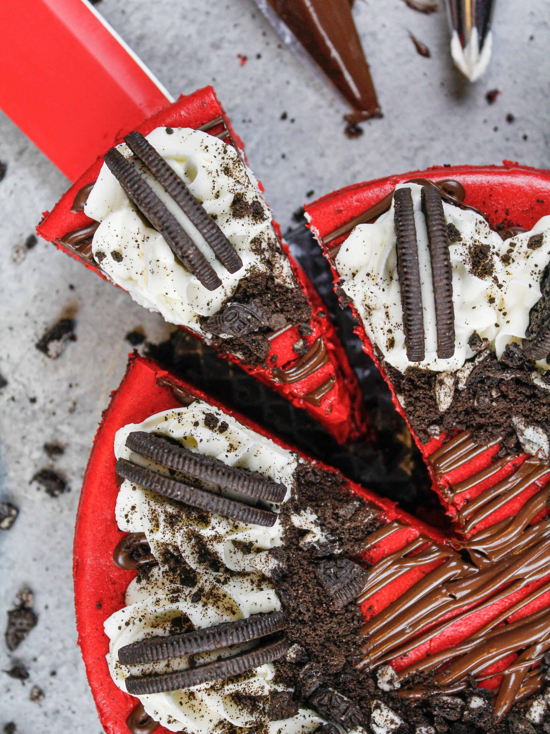 image of red velvet oreo cheesecake that's been cut and is having a slice pulled out to be eaten