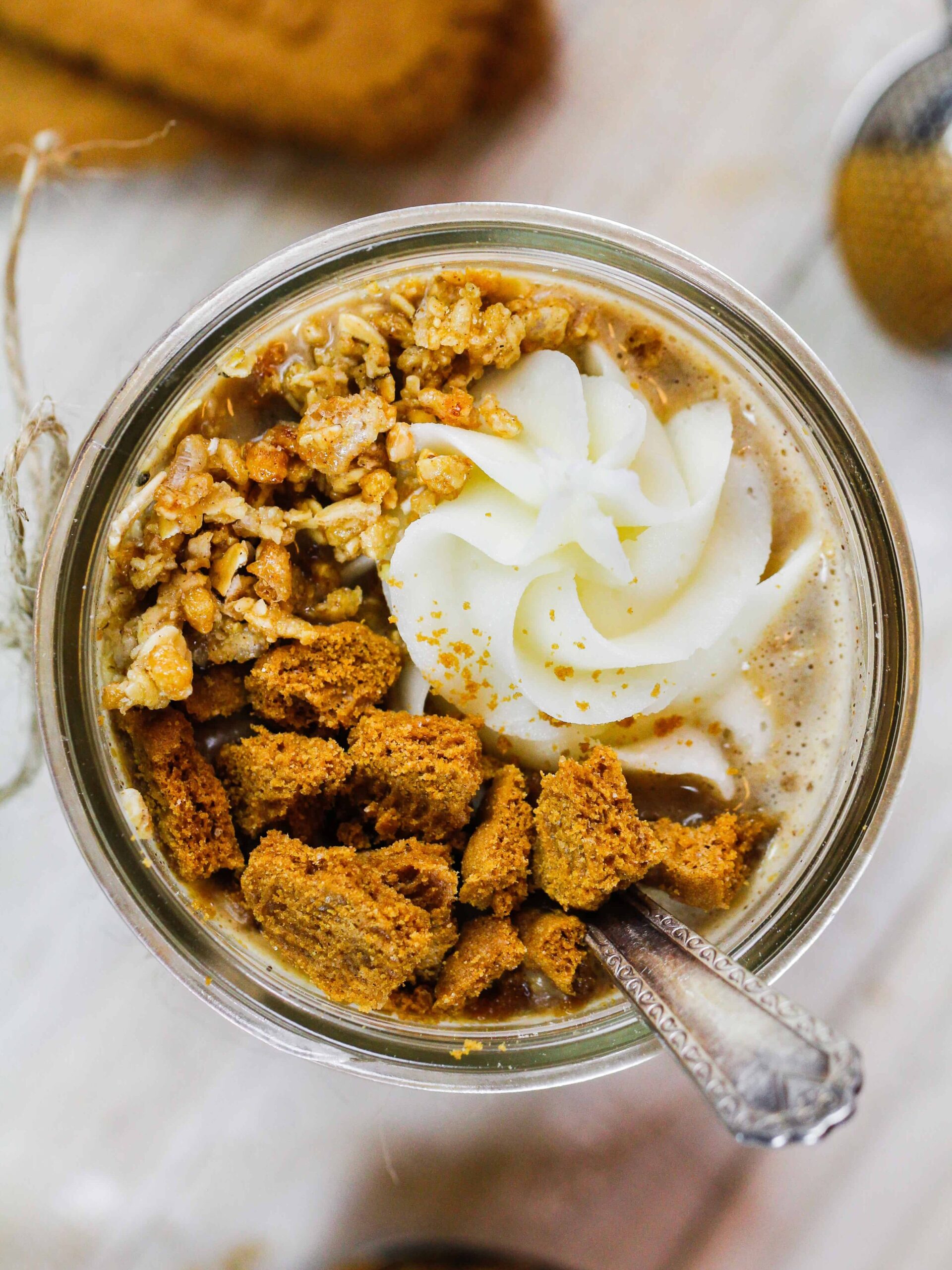 image of a mason jar overhead filled with cookie butter overnight oats and topped with whipped cream, chopped up biscoff cookies and some granola
