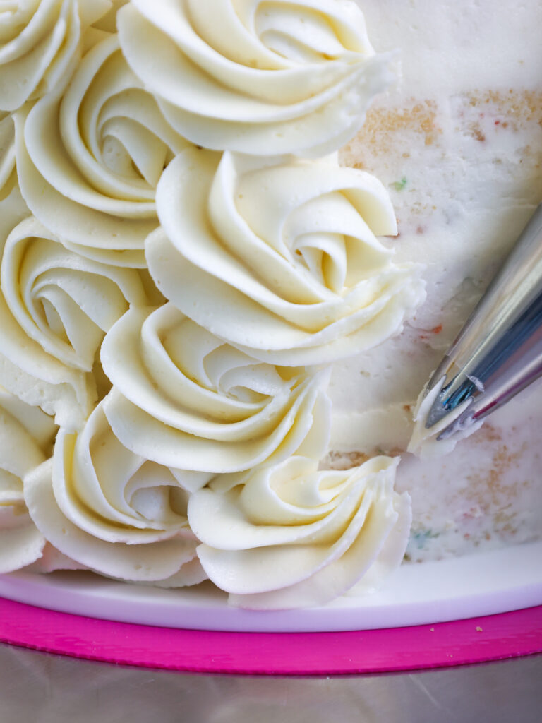 image of vanilla buttercream being piped onto a cake with a wilton 1m frosting tip