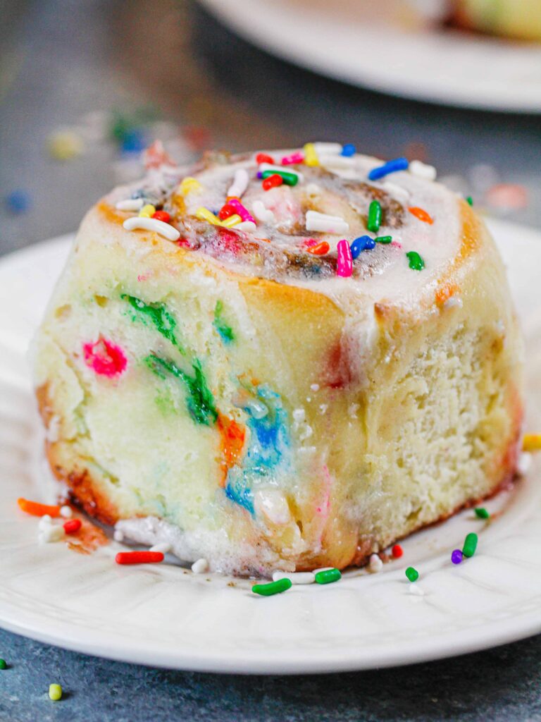 image of a funfetti cinnamon roll made with sprinkles and topped with vanilla icing