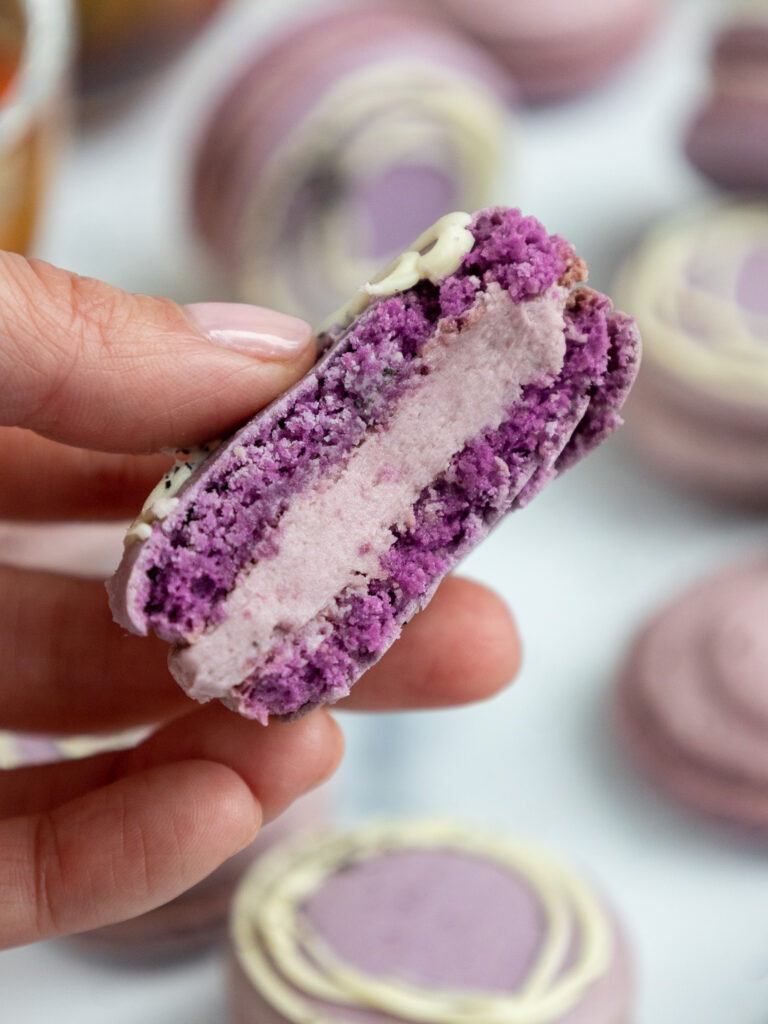 image of an earl grey macaron that has been bitten into to show its earl grey buttercream filling
