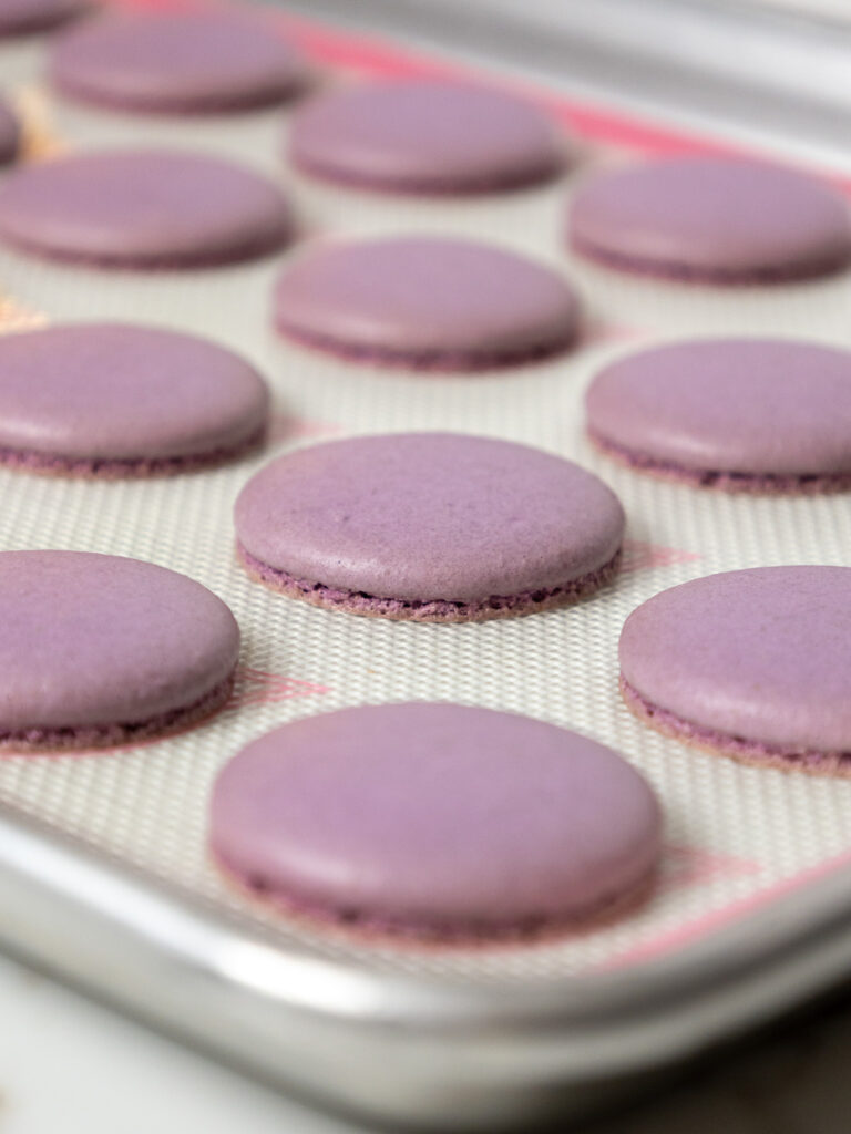 image of light purple macaron shells that have been baked and are cooling on a silpat mat