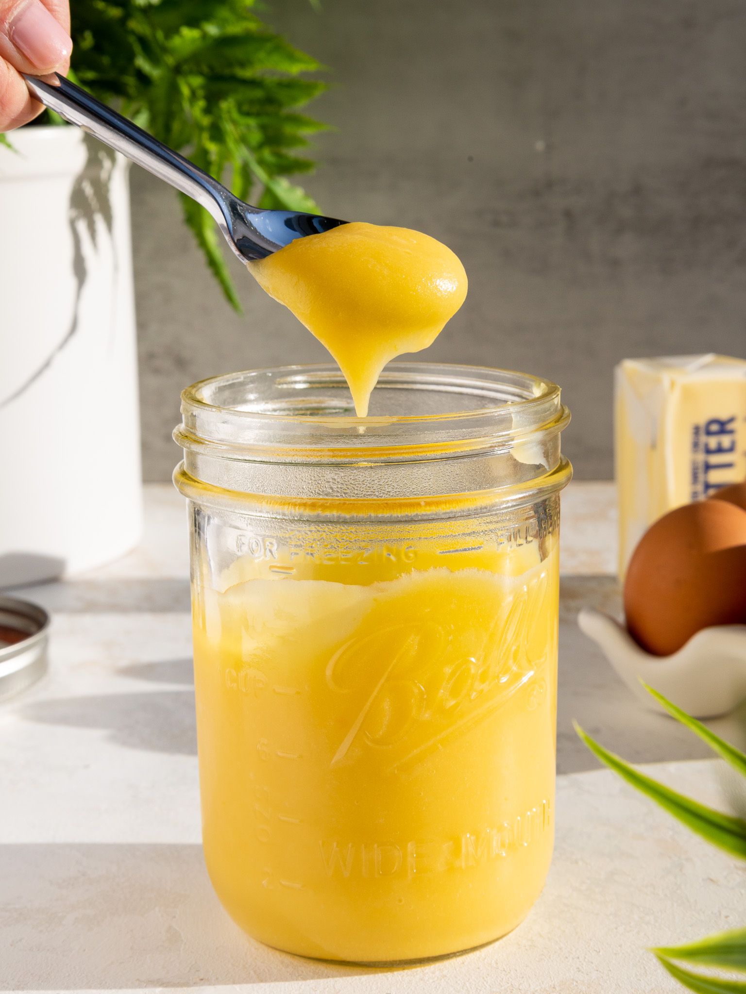 pineapple curd that's being spooned out of a mason jar to show it's thick texture