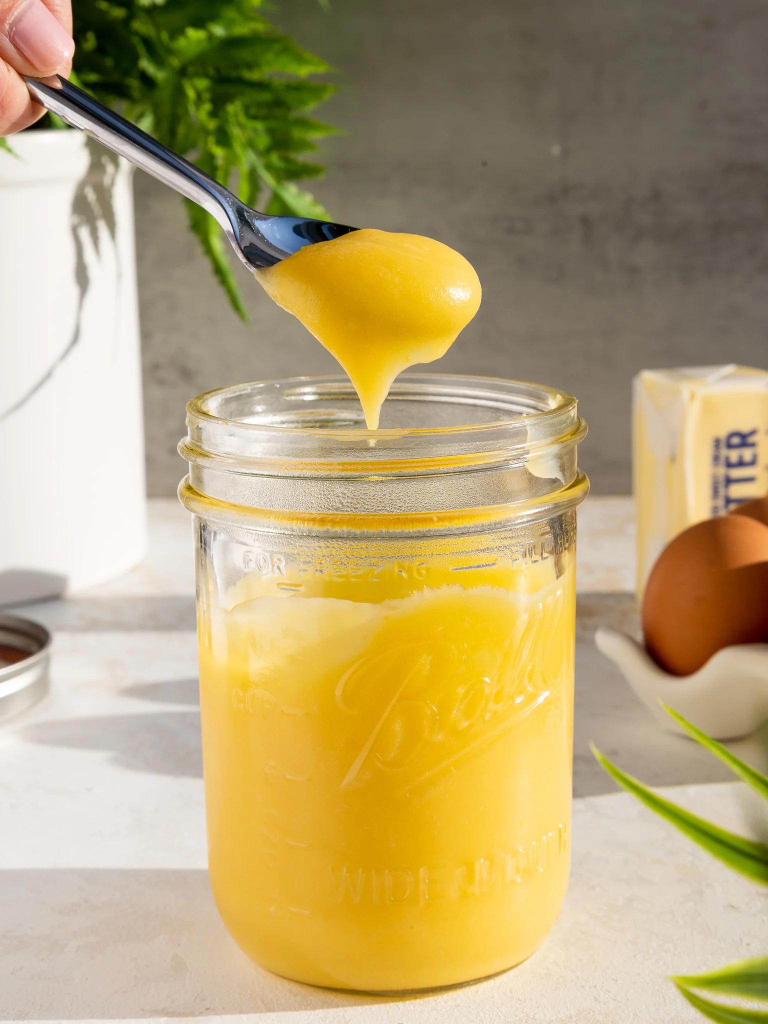 pineapple curd that's being spooned out of a mason jar to show it's thick texture