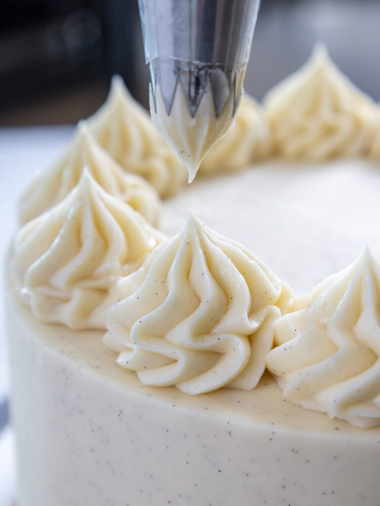 image of swirls being piped on top of a cake with vanilla bean buttercream