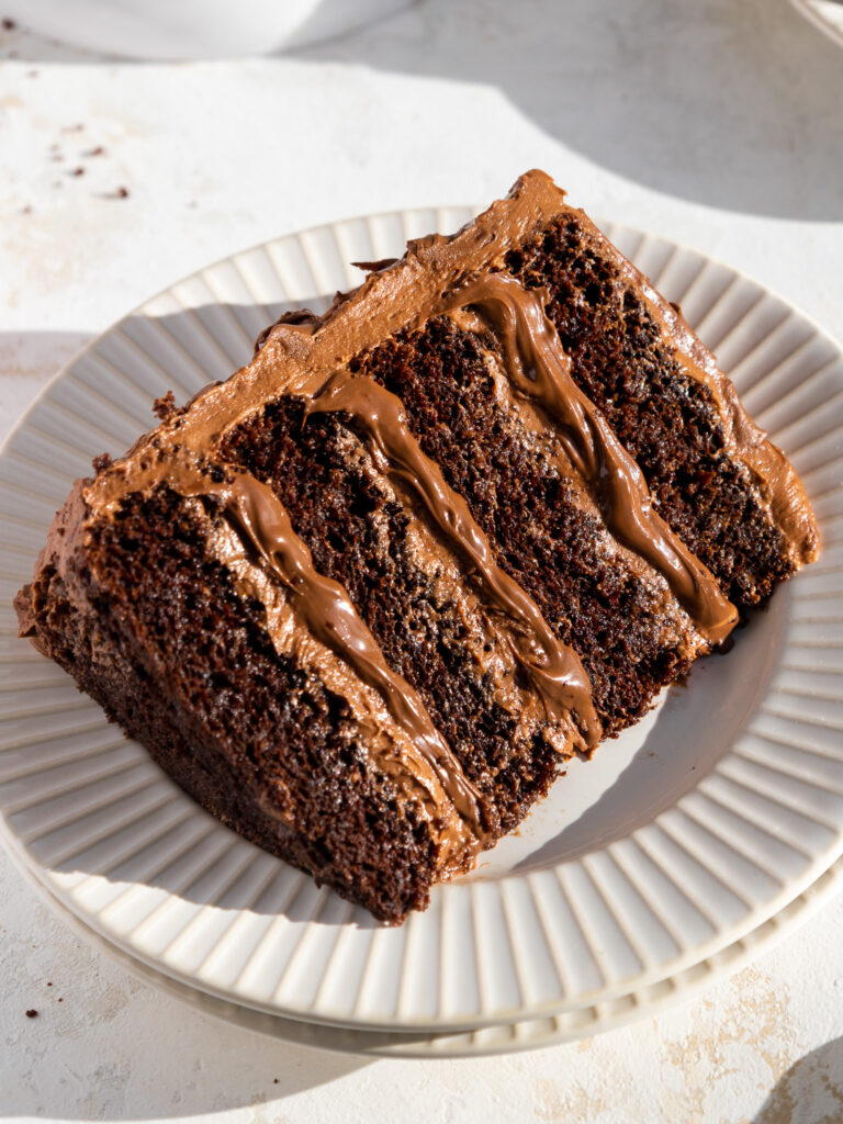 image of a slice of Nutella cake on a plate that's been cut into to show its Nutella buttercream filling