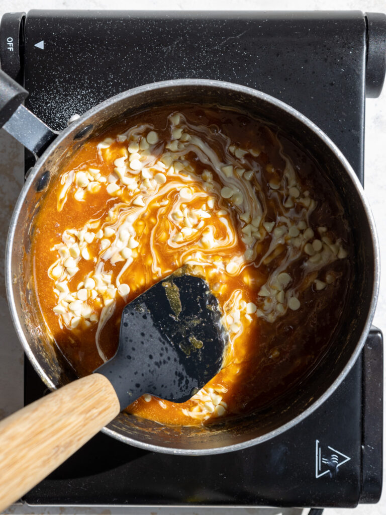 image of white chocolate chips being mixed into caramel to make it thicker