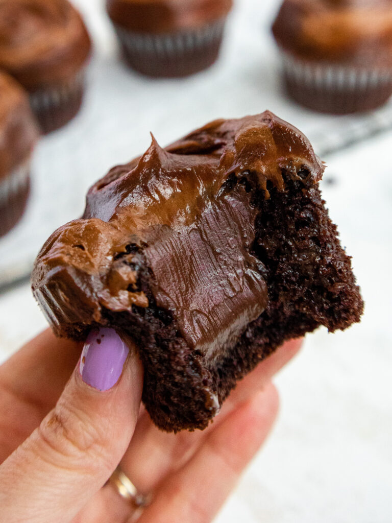 image of death by chocolate cupcakes that have been frosted with chocolate buttercream and chocolate ganache and are sitting on a wire rack lined with parchment paper