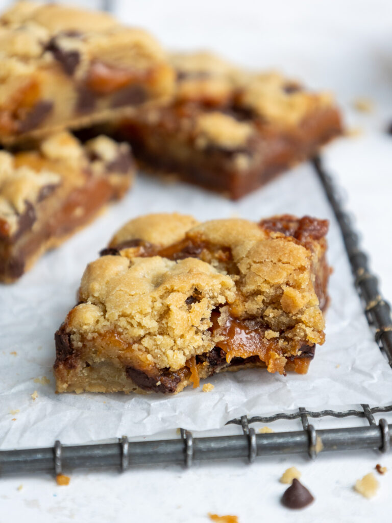 image of caramel cookie bar that's been bitten into to show its caramel layer in the center