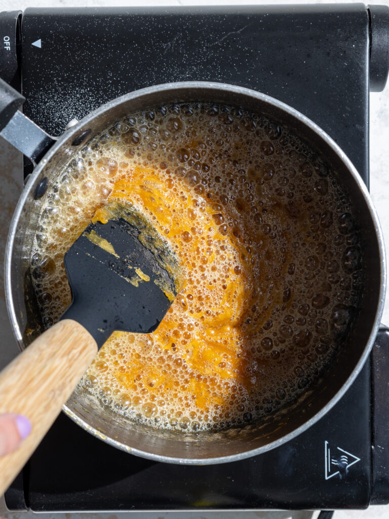 image of butter being mixed in melted sugar to make caramel
