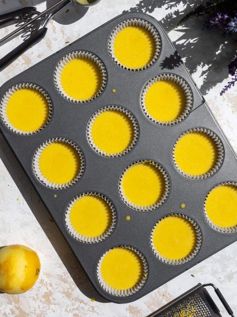 image of lemon cupcake batter that's been poured into cupcake liners in a muffin pan and is ready to be baked