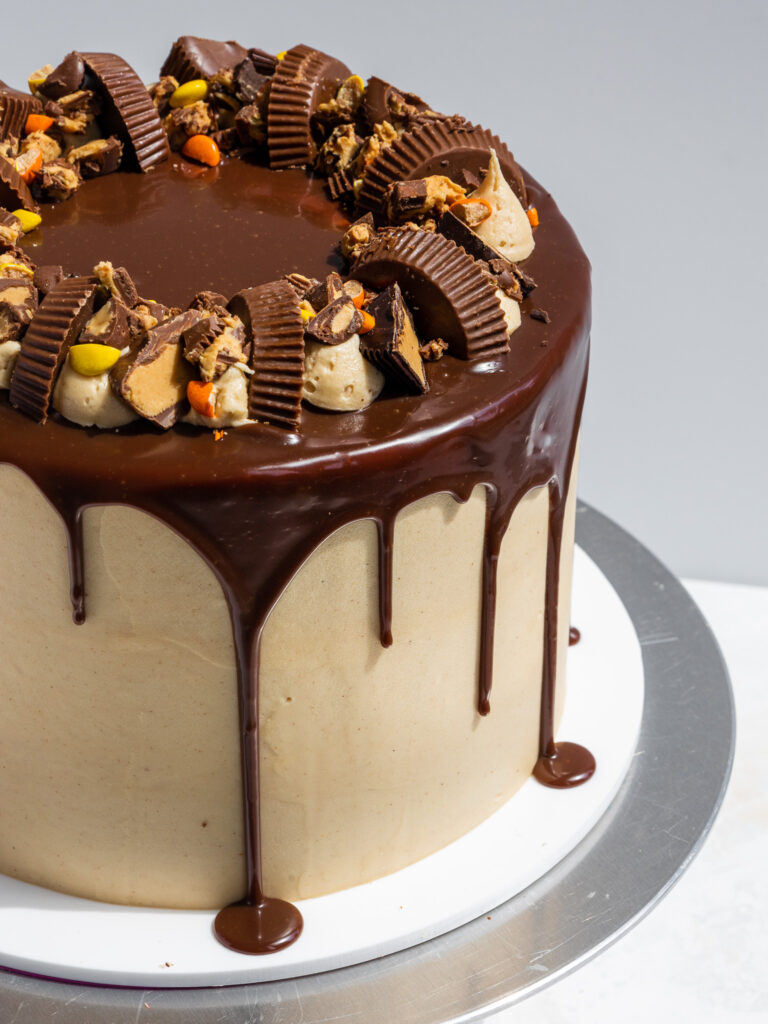 image of a reese's chocolate peanut butter cake that's been decorated with a chocolate drip and reese's candies
