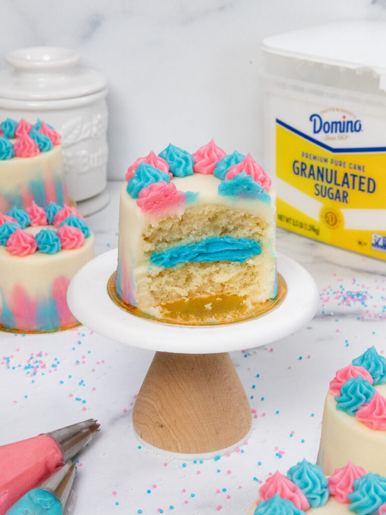 image of a mini gender reveal cake that's been cut into to show the blue frosting that it's filled with