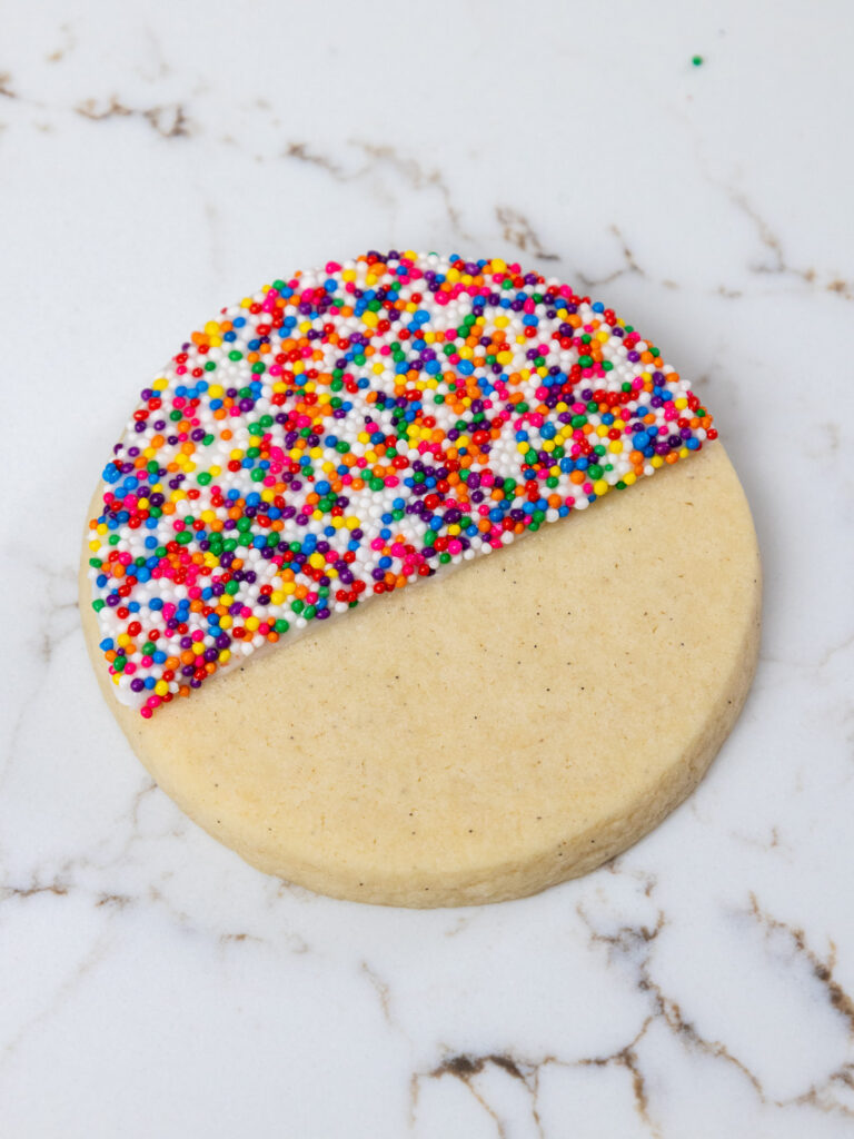 image of a sugar cookie that's been half covered in royal icing and sprinkles