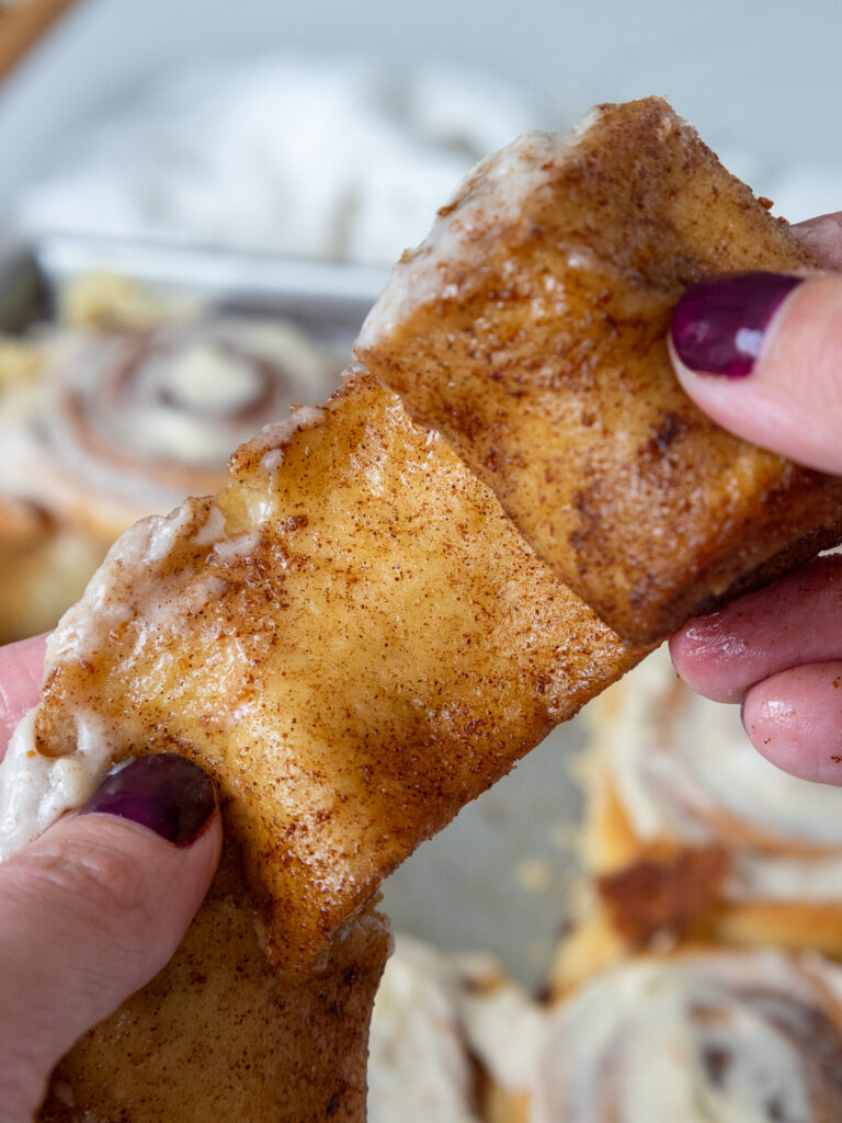 image of a brown butter cinnamon roll being unwound to show its gooey filling