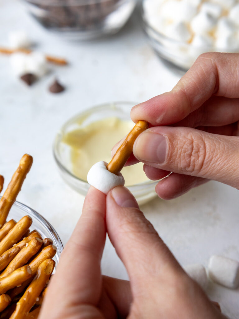 image of a marshmallow being pressed into a pretzel stick to make strawberry turkeys