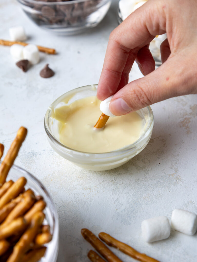 image of a pretzel being dipped into melted white chocolated