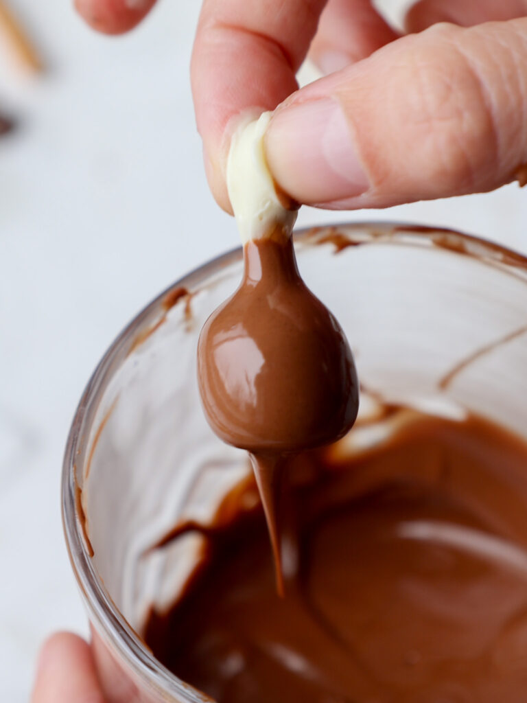 image of a pretzel turkey leg being dipped in milk chocolate