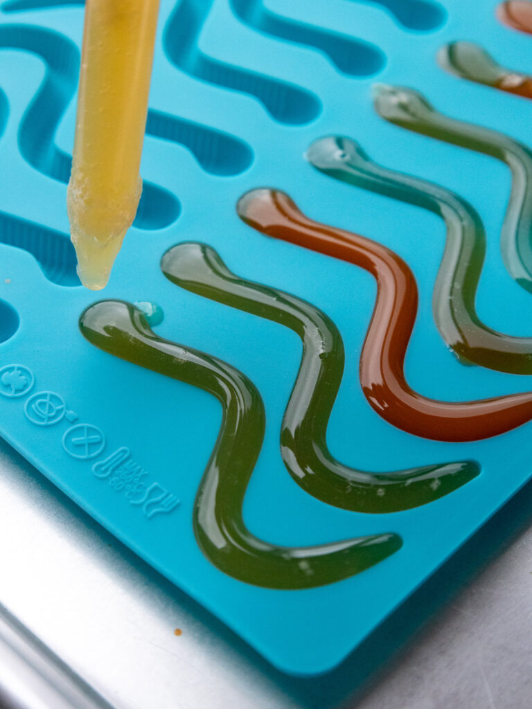 image of a silicon mold being filled with fruit juice to make homemade gummy worms