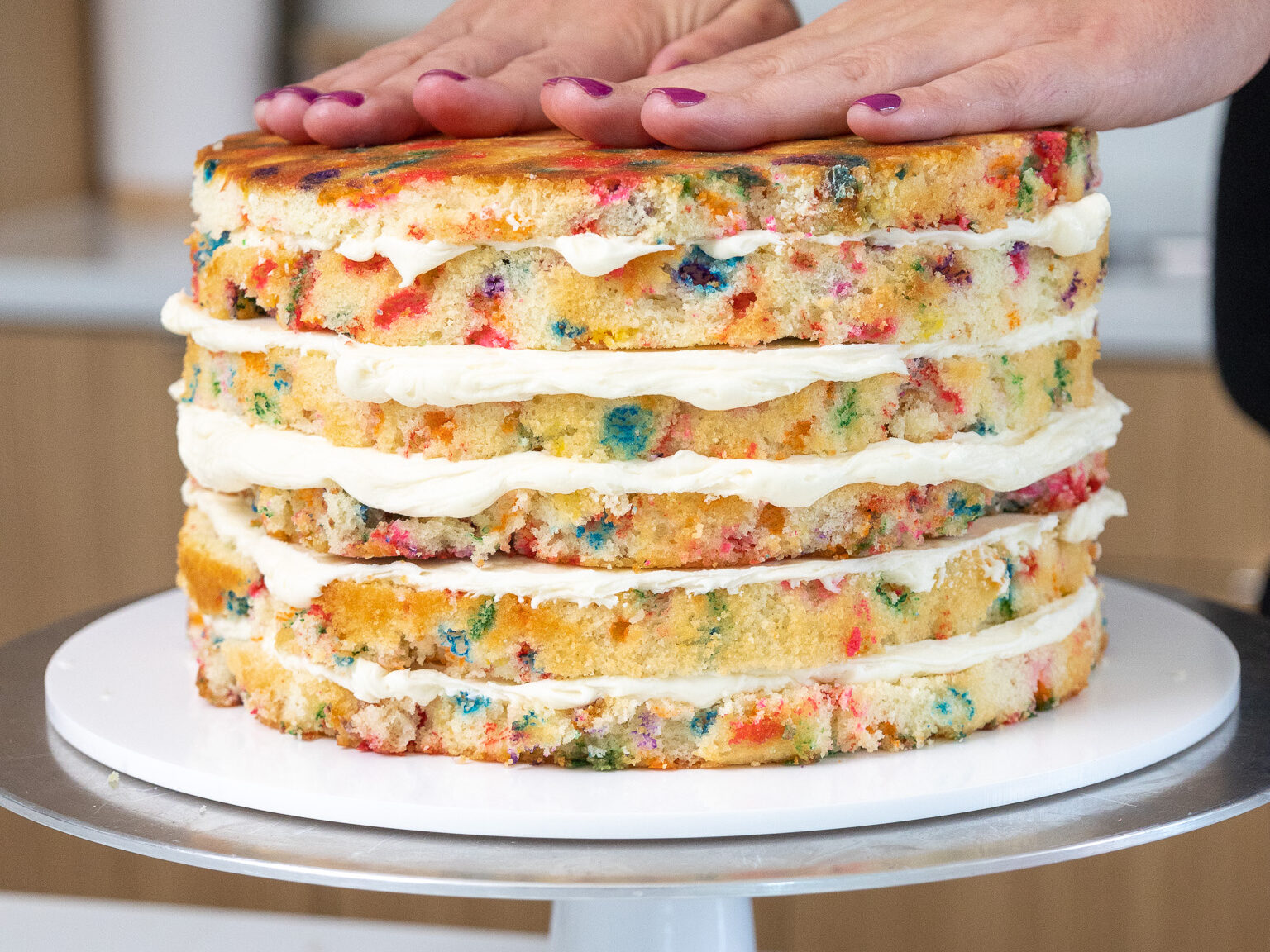 image of funfetti cake layers being frosted and stacked to make a funfetti layer cake