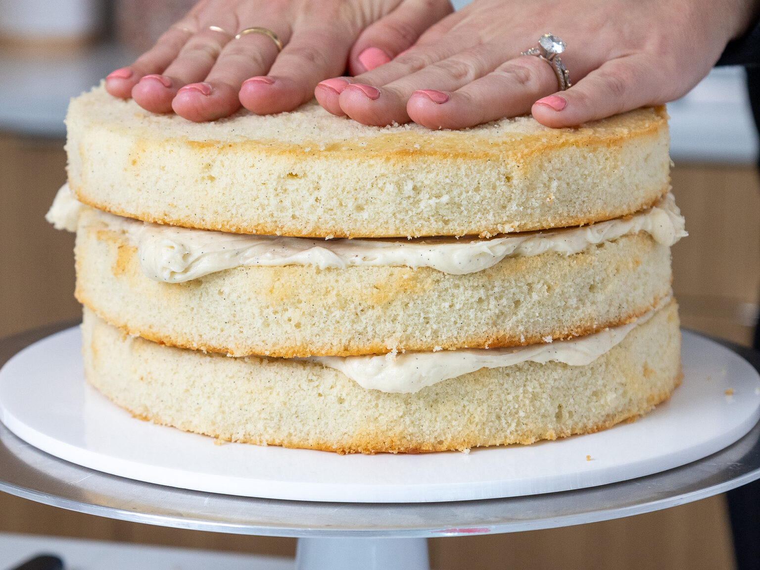 image of vanilla bean cake layers being stacked with buttercream