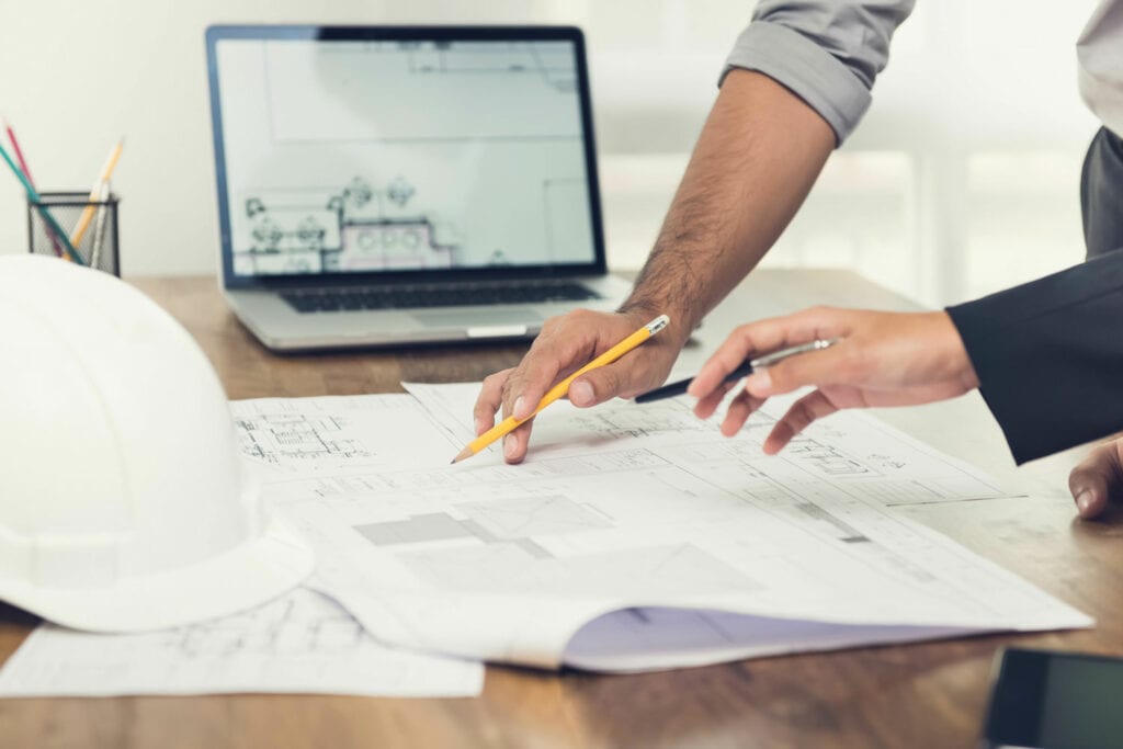 Two engineers going over blueprint plans of a basement renovation project
