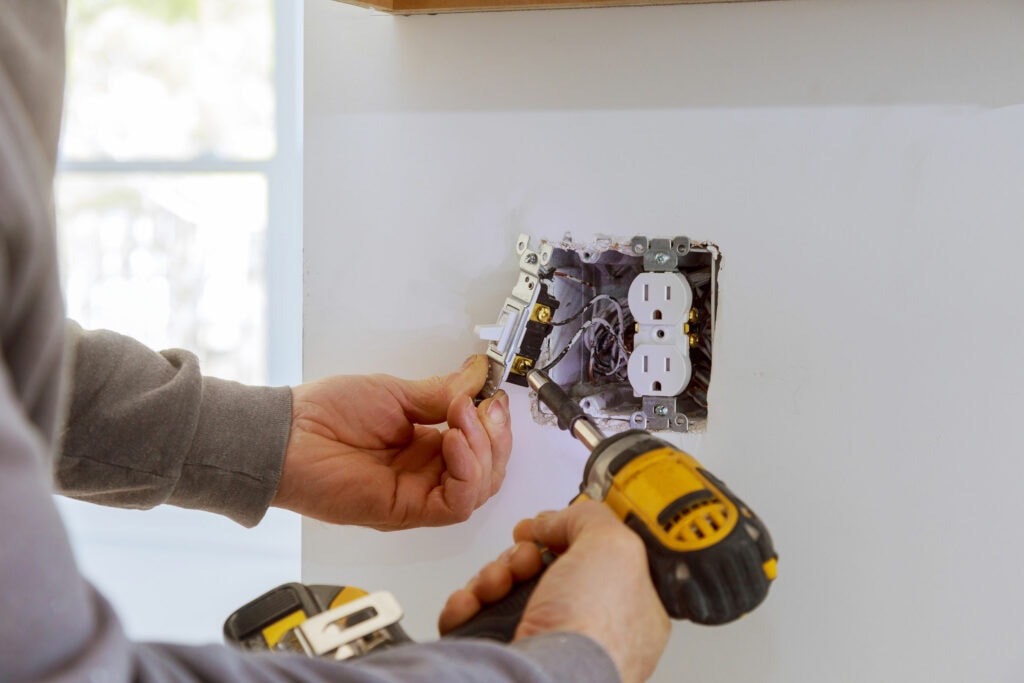 An electrician fixing an indoor electrical outlet