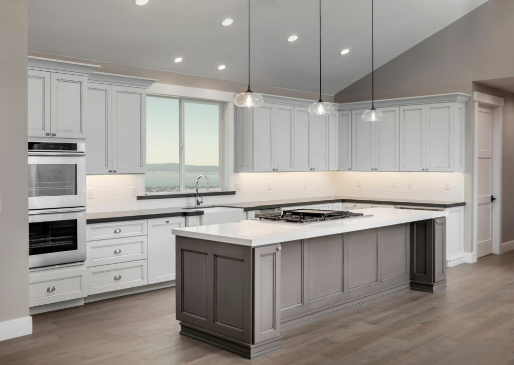 Modern kitchen, with a big island, recessed lights, white cabinets, and new flooring