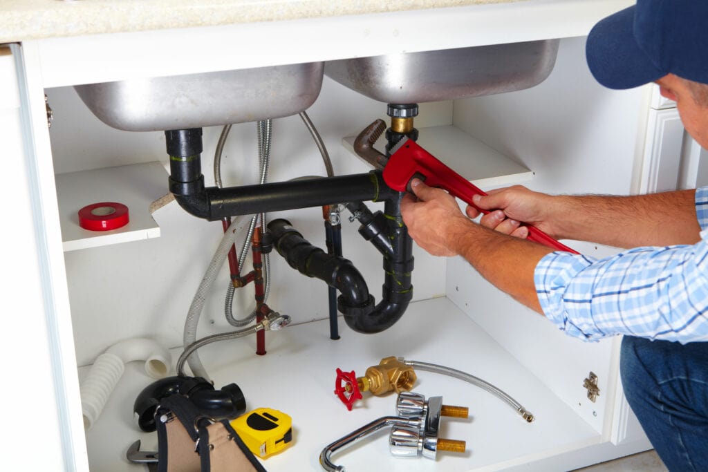 Plumber fixing a pipe under a kitchen sink