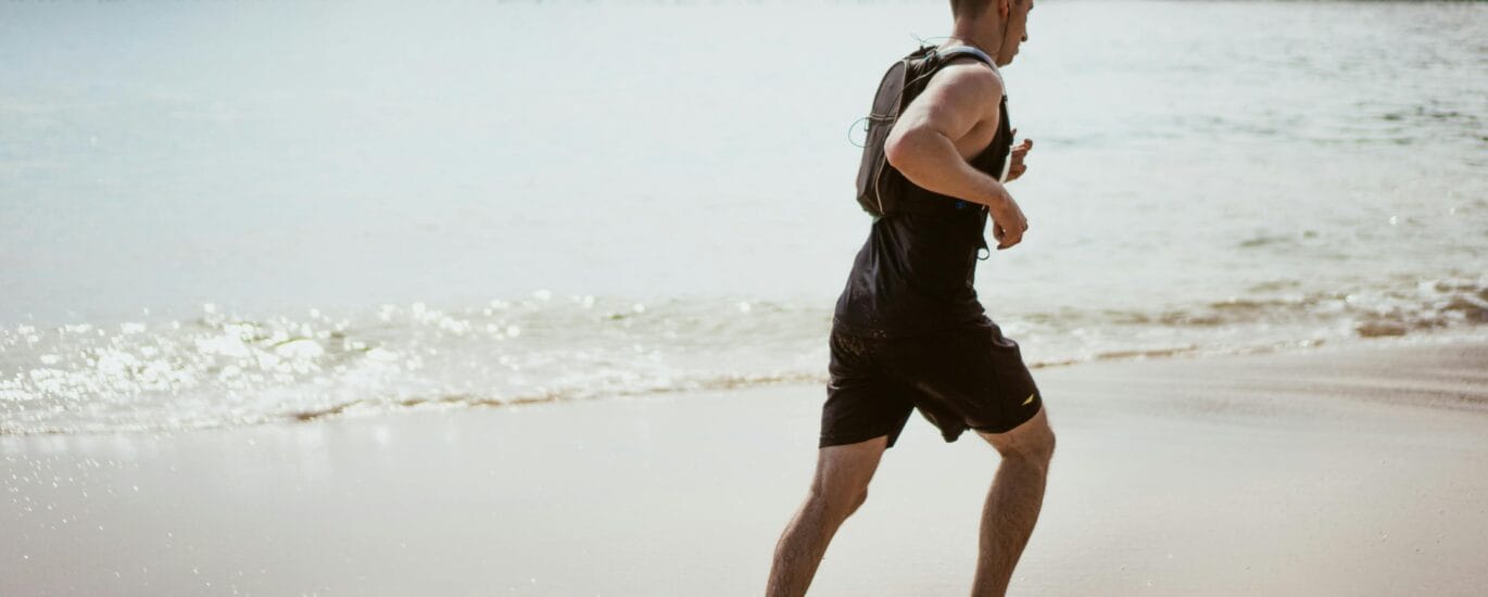 Homem correndo na praia durante o dia, praticando cardio em jejum com foco na queima de gordura