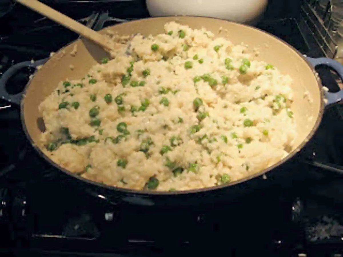 Pot of chicken and rice risotto on a black stove.