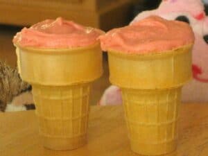 Image shows double chocolate cupcakes with strawberry frosting on cones.