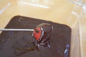 Dipping a strawberry on a fondue fork into chocolate fondue.