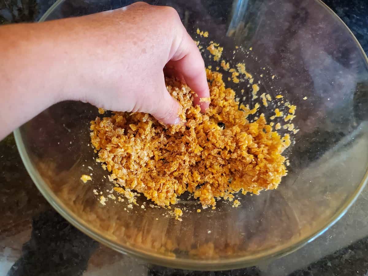Mixing cereal crumbs with butter in a clear bowl.