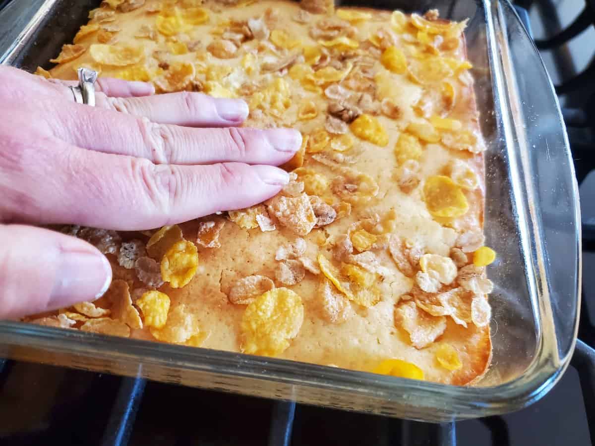 Pressing cereal into the top of vanilla orange cheesecake bars.