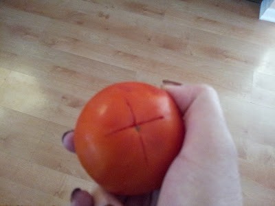 Fresh tomato with an X cut into the bottom.