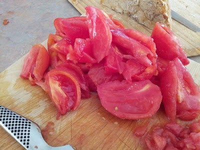Tomatoes cut up and seeded sitting on a wooden cutting board.