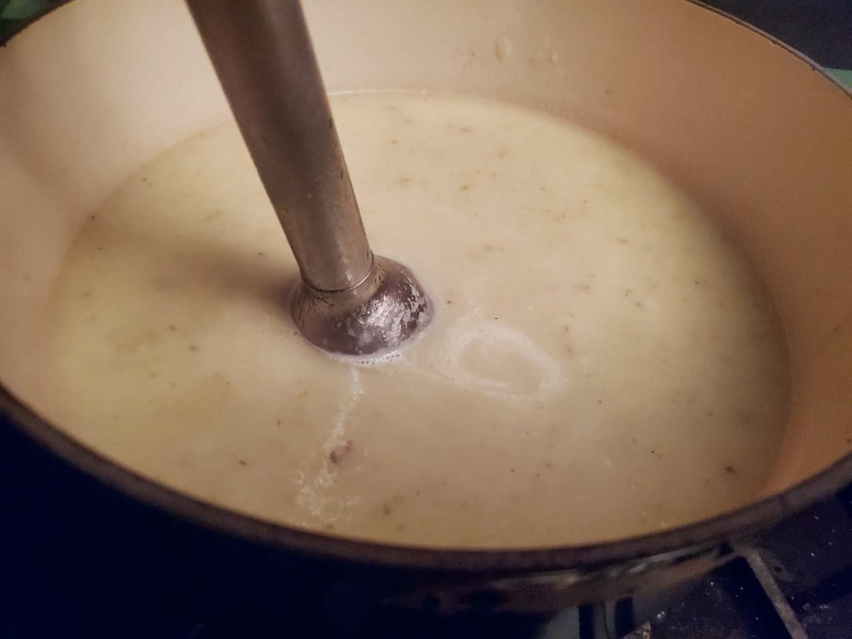 Blending cream of celery soup with an immersion blender.