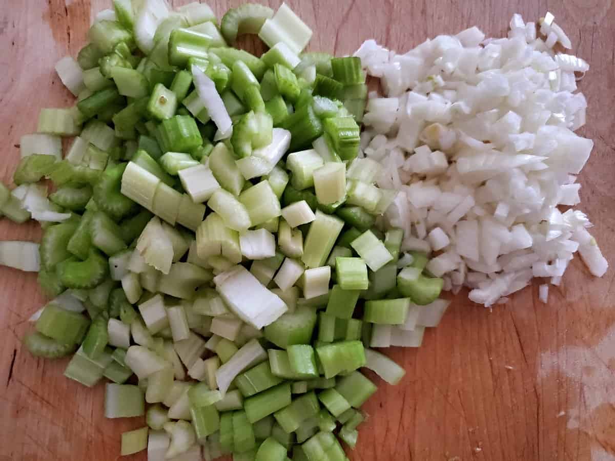 Chopped onion and celery on a wooden cutting board.