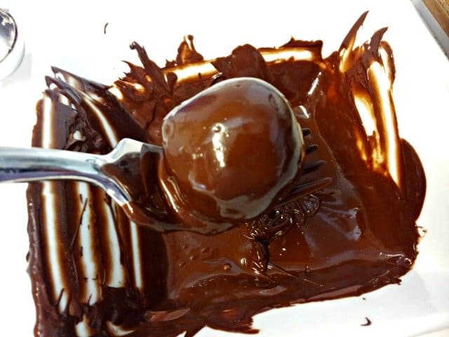 Shaking excess chocolate from chocolate chip cookie dough truffles
