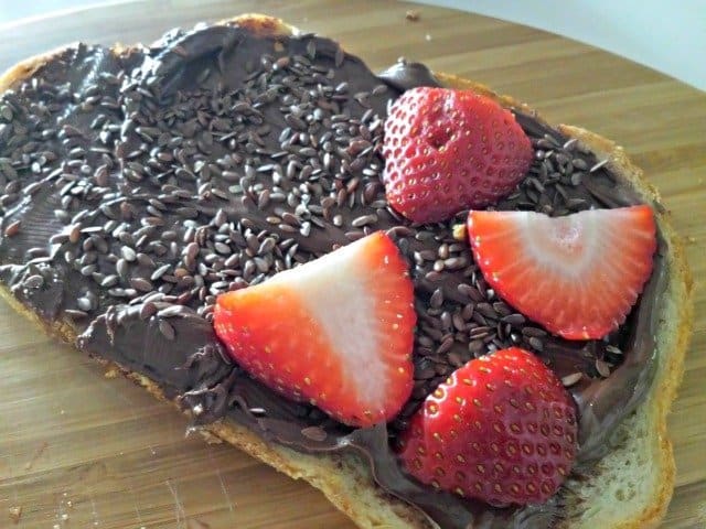 Layer the ingredients for your sweet protein sandwich: first Nutella, then flax seeds, strawberries, and finally apple slices