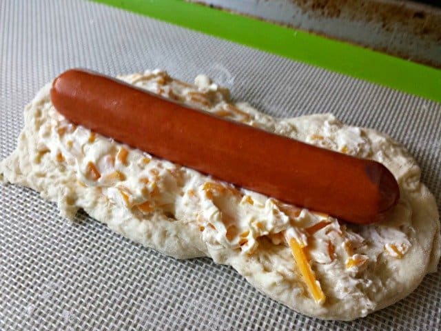 Adding cheesy mixture to bagel dogs