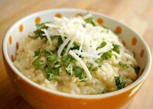 Orange bowl with parmesan risotto topped with fresh parsley.