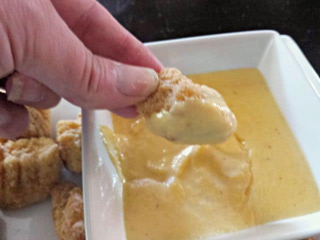 Dipping popcorn chicken into Fantastic Four cheesy dipping sauce