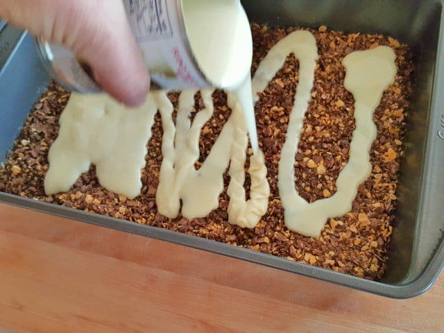 Pour sweetened condensed milk over cereal layer in seven layer bars