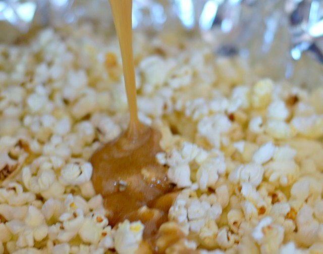 Pour hot caramel onto popcorn