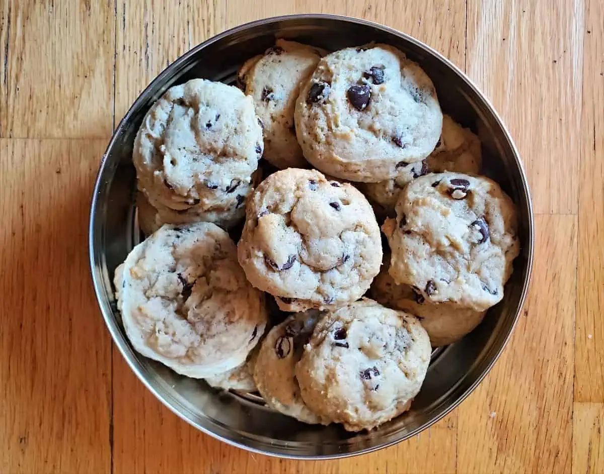 Tin of chocolate chip cookies on a wooden background.