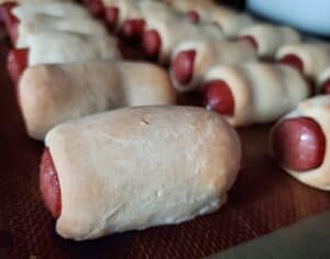 Baked bagel dogs lined up on a silpat.