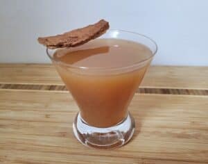 Hot apple cider rum in a cocktail glass topped by a cinnamon stick.