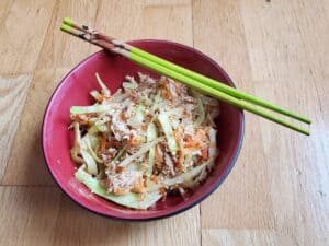 Overhead of a red bowl of egg roll in a bowl with chopsticks resting on the bowl.